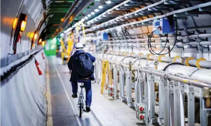  ??  ?? A man rides his bicycle along the beam line of the Large Hadron Collider. Photograph: Valentin Flauraud/AFP via Getty Images