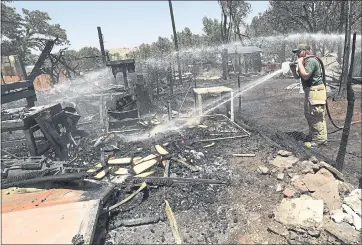  ?? PHOTOS BY THE ASSOCIATED PRESS ?? A Green River firefighte­r cleans up after a brush fire near Pack Creek in Moab, Utah. The fire destroyed homes in the Utah tourist town, while several thousand people in Colorado and Wyoming fled multiple wildfires scorching those areas.