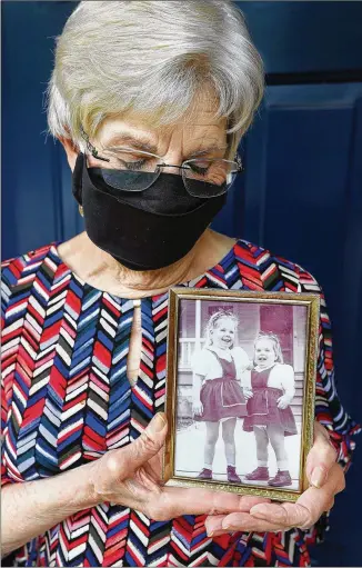  ?? PHOTOS BY CURTIS COMPTON / CCOMPTON@AJC.COM ?? Clarissa Strickland, whose sister Nan Durrett, 74, died last month after a horrible experience at an assisted living facility that went on lockdown to thwart coronaviru­s, holds a family picture of herself (left) at age 4 and her sister at age 3 at home last week in Lilburn.