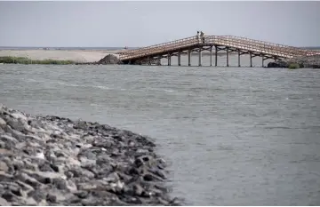  ??  ?? Visitors cross a bridge on the Marker Wadden, artificial islands located in the Markermeer lake in the Netherland­s.