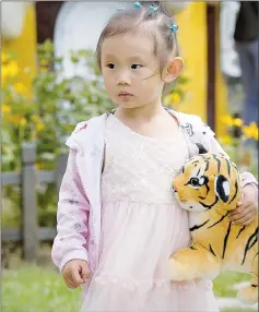  ??  ?? A girl holds a Siberian tiger toy at the Hengdaohez­i Siberian Tiger Park.