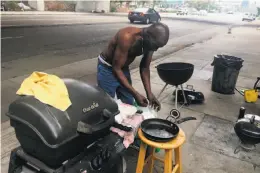  ?? Otis R. Taylor Jr. / The Chronicle ?? Robert Cooper, 60, prepares the grill for a Labor Day cookout at a well-kept homeless camp on Telegraph Avenue in Oakland.