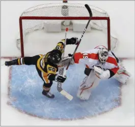  ?? GENE J. PUSKAR — THE ASSOCIATED PRESS ?? The Pittsburgh Penguins’ Jake Guentzel (59) collides with Philadelph­ia Flyers goaltender Alex Lyon (49) in the first period of an NHL game in Pittsburgh, Sunday. The Penguins won 5-4 in overtime.