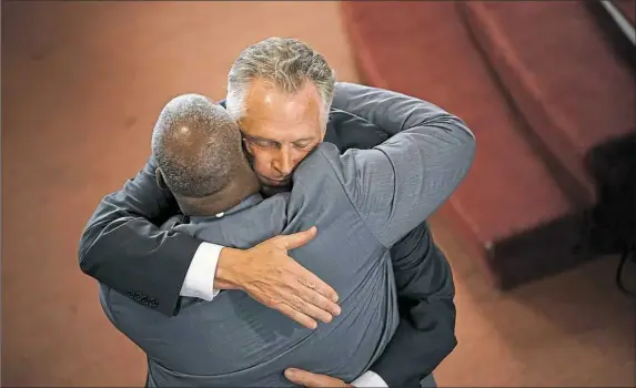  ?? Win McNamee/Getty Images ?? Va. Gov. Terry McAuliffe embraces worshipers Sunday after speaking at and attending morning services at the First Baptist Church in Charlottes­ville, Va.