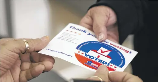  ?? ASHLEE REZIN/SUN-TIMES ?? A woman receives her “I voted!” sticker after voting in the 2024 primary at the Northtown Branch of the Chicago Public Library.