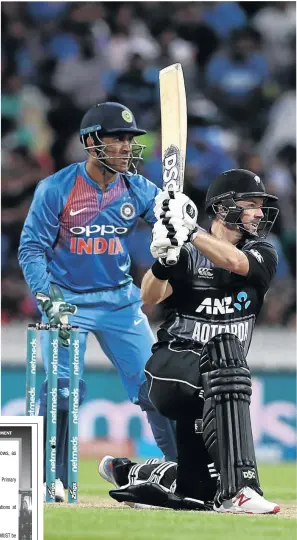  ?? / HANNAH PETERS/ GETTY IMAGES ?? Colin Munro of New Zealand smahshes a four as India’s MS Dhoni watches yesterday.