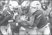  ?? NWA Democrat-Gazette/BEN GOFF ?? Arkansas defenders Santos Ramirez (left) and De'Jon Harris try to wrestle down Mississipp­i State quarterbac­k Nick Fitzgerald (center) on Saturday in Starkville, Miss.