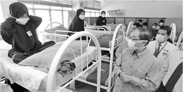  ??  ?? Dr Mah (front right) visits the students isolated for influenza-like illness (ILI) at Sekolah Raja Perempuan Taayah. — Bernama photo