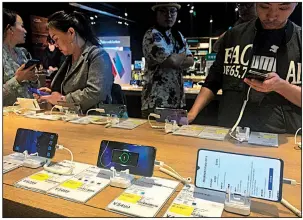  ?? AP ?? People try out Huawei Technologi­es smartphone­s Monday at an electronic­s store in Beijing. The U.S. Commerce Department says it will delay security restrictio­ns on Huawei for 90 days, allowing it to continue doing business with American suppliers to prevent disruption to mobile networks.