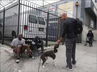  ?? PHOTOS BY DAMIAN DOVARGANES THE ASSOCIATED PRESS ?? Dr. Kwane Stewart asks people who's the owner of a dog in the skid row area of Los Angeles on June 7. Stewart, 52, is a lifelong animal lover who grew up in Texas and New Mexico trying to save strays — or at least care for them any way he could.