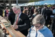  ?? PHOTO PROVIDED ?? Author and noted paleontolo­gist Neil Shubin, left, autographs a steel beam during groundbrea­king ceremonies for Skidmore College’s new Center for Integrated Sciences.