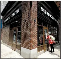  ?? AP/MATT SLOCUM ?? A woman peers into a Starbucks coffee shop in Philadelph­ia that was among more than 8,000 of the chain’s stores that closed Tuesday for anti-bias training.
