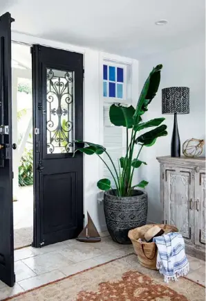  ??  ?? FRONT ENTRANCE In dramatic contrast with the home’s crisp white walls, the inky wrought-iron front doors (top left) make a memorable first impression. “These doors were here when we bought the house,” says Terry. “I feel they add a lot of character to the home.” Resting on a whitewashe­d console from The Boathouse Home, a glass buoy found at Beachwood Designs pays homage to the location, while the rug from Karavan is also a natural fit with the home’s relaxed coastal aesthetic.