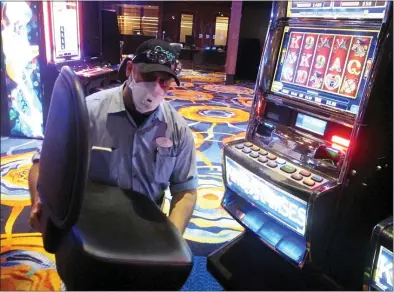  ?? WAYNE PARRY — THE ASSOCIATED PRESS ?? A worker at the Ocean Casino Resort in Atlantic City N.J. removing the chair from a slot machine earlier this month, part of distancing measures to help prevent the spread of the coronaviru­s.