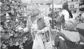  ?? ALGERINA PERNA/BALTIMORE SUN PHOTOS ?? Andrea Esbrandt, left, shops at Stebbins Anderson with her grandchild­ren, right, and their mom, Kirstin Esbrandt, background right, at the Shops at Kenilworth on Small Business Saturday, the American Express-created holiday on the day after Black Friday.
