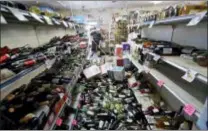  ?? MARCIO JOSE SANCHEZ — THE ASSOCIATED PRESS ?? Bottles of wine are strewn in the middle of an aisle as Victor Abdullatif, background center, mops inside of the Eastridge Market, his family’s store, Saturday in Ridgecrest, Calif.