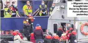  ??  ?? Migrants are brought into Dover by Border Force officers yesterday