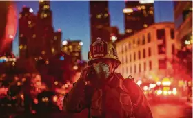  ?? Apu Gomes / AFP via Getty Images ?? A Los Angeles Fire Department public informatio­n officer speaks on the phone after a fire in a single-story commercial building sparked an explosion Saturday.