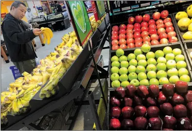  ?? AP/ANDY WONG ?? A man chooses bananas near imported apples from the United States at a supermarke­t Monday in Beijing. China on Monday imposed $3 billion in previously announced tariffs on 128 imported goods, including apples originatin­g in the U.S.