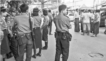  ?? — AFPphoto ?? A group of Myanmar Muslim men (seen at right) gather in the street outside a private meeting hall while armed policemen secure the area after hardline Buddhist nationalis­ts stopped a Muslim ceremony marking the Prophet Mohammed’s birthday at a YMCA...