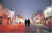  ??  ?? Security personnel wearing face masks patrol Wangfujing Street in Beijing.