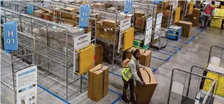  ?? Justin Sullivan/Getty Images ?? A worker moves a package at an Amazon delivery station in Alpharetta, Ga. Amazon is changing the fees it charges sellers, including on shipments sent to fulfillmen­t centers.