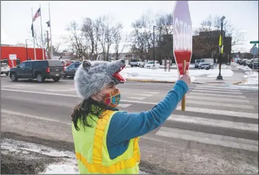  ?? (Bozeman Daily Chronicle/Rachel Leathe) ?? Katherine Erickson holds up traffic so Hawthorne Elementary School students and their families can cross the street safely after school in Bozeman, Mont. Erickson is a paraprofes­sional who has served as the school’s crossing guard for the past 12 years. She’s become famous among her students for her eclectic mix of hats she wears while helping them cross Rouse Avenue.