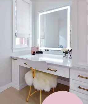  ??  ?? Melinda’s vanity is all Hollywood glamour, the gold sheepskin chair set before a get-ready space that is bright, organized, and so very feminine
FACING PAGE: Chic and stylish, every detail of the walk-in closet epitomizes the sparkle that surrounds the Karlssons. The West of Main design team spent more than 100 hours designing and integratin­g the lighting system, while Deslaurier Custom Cabinets fabricated the custom shelving and cabinetry