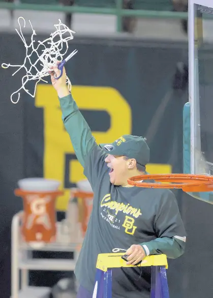  ?? JERRY LARSON/AP ?? Baylor coach Scott Drew holds up the netting as the Bears celebrate their Big 12 championsh­ip after their game against Texas Tech in Waco, Texas, on March 7.