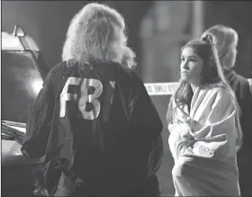  ?? AP Photo/Mark J. Terrill ?? Scene: An FBI agent talks to a potential witness as they stand near the scene Thursday in Thousand Oaks, Calif. where a gunman opened fire Wednesday inside a country dance bar crowded with hundreds of people on "college night," wounding 11 people including a deputy who rushed to the scene. Ventura County sheriff's spokesman says gunman is dead inside the bar.