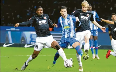  ?? Foto: Jörg Carstensen, dpa ?? Es war ein zähes Ringen zwischen dem FC Augsburg und Hertha BSC Berlin, das mit einem 2:2 endete. Hier bremsen die Augsburger Kevin Danso (links) und Martin Hinteregge­r (rechts) den Herthaner Mathew Leckie aus.