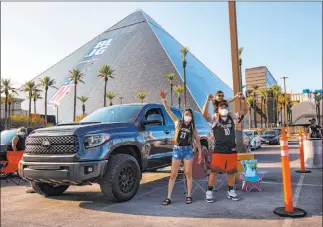  ?? Chase Stevens Las Vegas Review-journal @csstevensp­hoto ?? Las Vegas Aces fans Kris Gabriel, left, and Aubrey Gabriel, 3, held by Armand Reyes, cheer at the start of a drive-in showing Thursday at the Luxor of the Aces’ game against the Lynx.