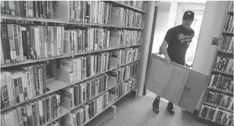  ?? NICK BRANCACCIO ?? Volunteer Todd Howson moves flood-damaged items at Nikola Budimir Library on Wednesday.