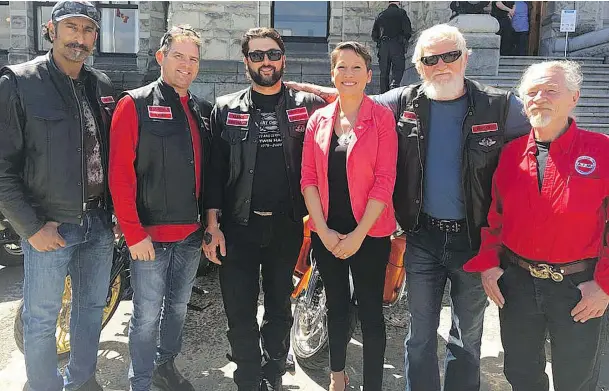 ??  ?? MLA Melanie Mark poses with Nick Elmes, left, and other members of the Florian’s Knights biker club — made up of firefighte­rs — at the legislatur­e.
