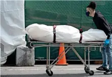  ?? AFP ?? VIRUS TRAGEDY: A body is moved from a refrigerat­ion truck serving as a temporary morgue to a vehicle at the Brooklyn Hospital Centre in the Borough of Brooklyn in New York. —