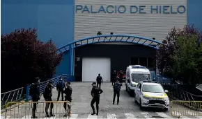  ?? AP ?? Police officers stand in front of Madrid’s ice rink which has been turned into a temporary morgue because of the Covid-19.