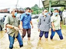  ??  ?? Bung wading through floodwater­s when visiting Kampung Pengkalan Bukit Garam.