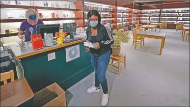  ??  ?? Sophomore Ainerance Babibanga (center) picks up books from the library, which is in the former china and housewares section of a department store.