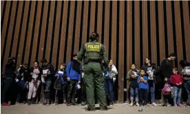  ?? Photograph: Étienne Laurent/EPA ?? A US border patrol looks on at people wait to have their identities checked and taken to a processing center in Yuma, Arizona, in June.