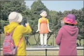  ?? ?? Visitors take photos near a model of the doll named “Younghee” that is featured in Netflix’s series “Squid Game” displayed at the Olympic park in Seoul, South Korea.