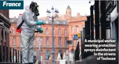  ??  ?? A municipal worker wearing protection sprays disinfecta­nt in the streets
of Toulouse