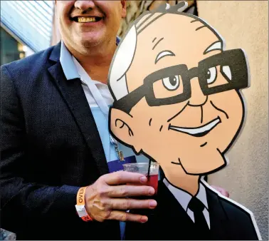  ?? REUTERS ?? A shareholde­r holds a drink posing with a cartoon Warren Buffett at the opening cocktail party for the Berkshire Hathaway Inc annual meeting, the largest in corporate America, in its hometown of Omaha, Nebraska, on Friday.