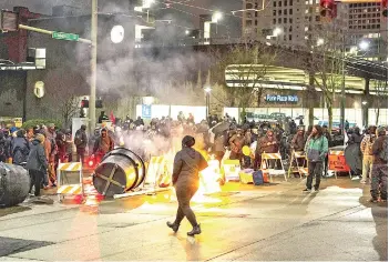  ?? — AFP photo ?? A demonstrat­or walks by a burning barricade in an intersecti­on in downtown Tacoma during an anti-police protest.