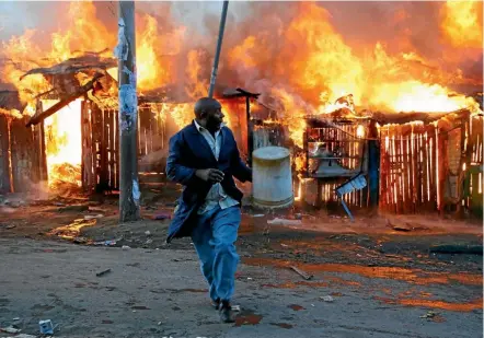  ??  ?? A man runs away after trying to douse a fire started by rioters in the Kawangware slum near Kenya’s capital, Nairobi, during election-related violence.