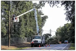  ?? Arkansas Democrat-Gazette/MITCHELL PE MASILUN ?? Entergy workers repair a power line that was taken down by a fallen tree on Arkansas 338 in Little Rock on Sunday. As of Sunday, there were still thousands of Arkansas residents without power.