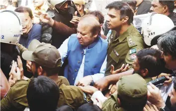  ?? AFP ?? Policemen escort former prime minister Nawaz Sharif (centre) as he arrives at the High Court to face treason charges in Lahore yesterday. The case centres around remarks made by Sharif suggesting Pakistani militants were behind the 2008 Mumbai attacks.
