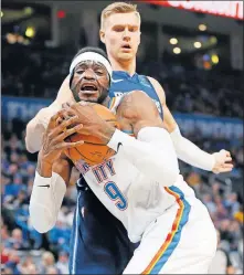  ?? BILLINGS/ THE OKLAHOMAN] ?? Oklahoma City's Nerlens Noel secures a rebound in front of Dallas' Kristaps Porzingis during Monday night's game at Chesapeake Energy Arena. Noel wore a clear facemask to protect a fractured cheek. [NATE