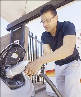  ?? AP ?? Darshan Brahmbhatt plugs a charger into his electric vehicle at the Sacramento Municipal Utility District charging station in Sacramento in this Sept. 17, 2015 file photo.