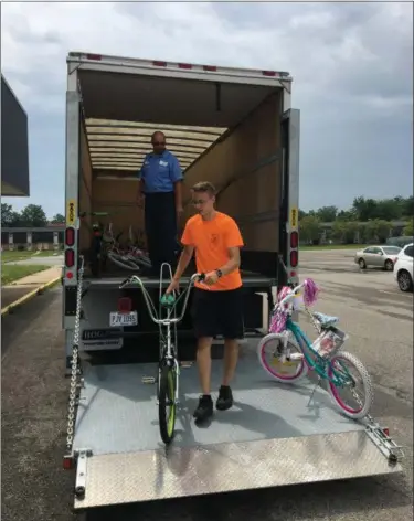  ?? DARRYL TUCKER — MORNING JOURNAL ?? Justin Lepkowski carries a bike from Heidelberg Distributi­ng Co. truck as Ray Ott looks on July 13.