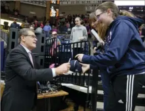  ?? JESSICA HILL — THE ASSOCIATED PRESS ?? Connecticu­t head coach Geno Auriemma signs autographs for fans after an NCAA basketball game against SMU, Saturday in Storrs, Conn. UConn extended its NCAA record winning streak to 99 games with an 83-41 win.